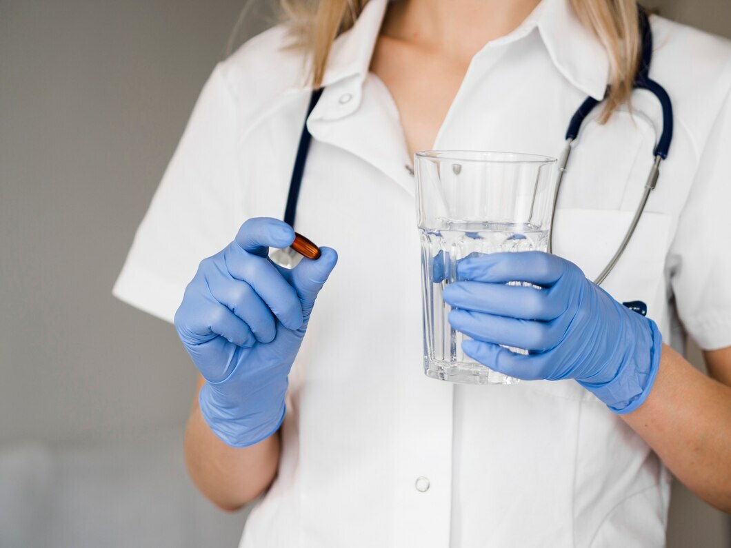 Медицинская сестра в перчатках держит стакан и таблетки